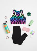 Colorful zebra print sports bra and black leggings with fitness accessories on a white background