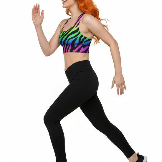 Woman wearing a colorful zebra print sports bra and black leggings on a white background