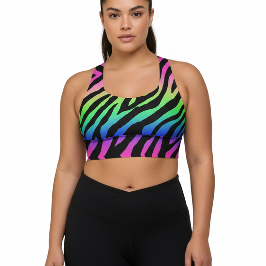 Woman wearing a colorful zebra print sports bra and black leggings on a white background