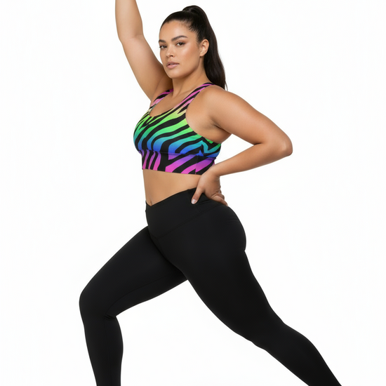 Woman wearing a colorful zebra print sports bra and black leggings on a white background