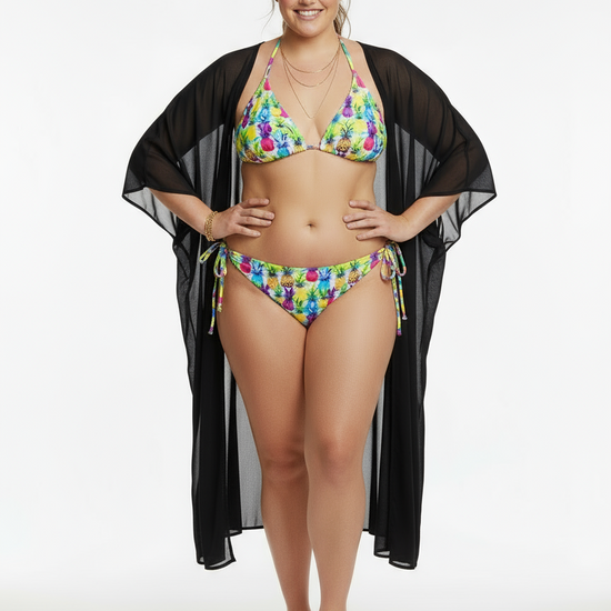 Model wearing Pixie & Sherbet ‘Tropic Like It’s Hot’ recycled string bikini with vibrant multicolour floral print, halter top and tie‑side bottoms, styled with sheer black cover‑up and matching headband.