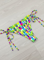 Colorful pineapple-patterned bikini on a light wooden floor
