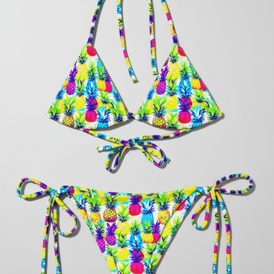 Flat lay of recycled string bikini in colourful yellow, pink, purple and blue pineapple print.