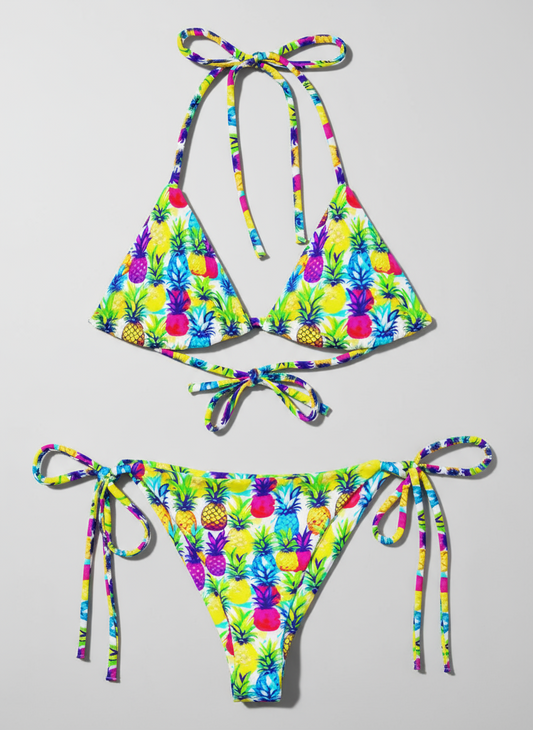 Flat lay of recycled string bikini in colourful yellow, pink, purple and blue pineapple print.