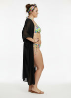 Woman wearing a colorful bikini and black cover-up on a white background