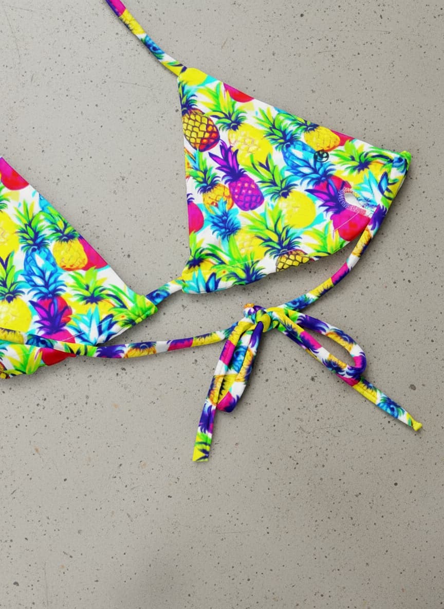 Colorful bikini set with pineapple pattern on a concrete surface