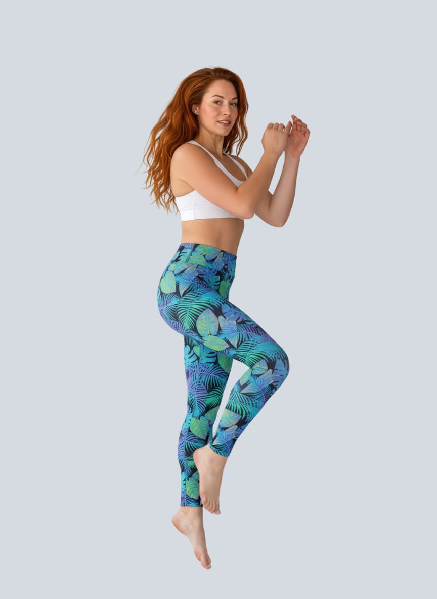 Woman wearing blue leaf-patterned leggings and a white sports bra on a light gray background