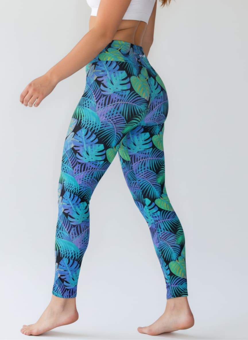 Person wearing blue tropical leaf pattern leggings on a white background