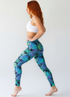 Woman wearing tropical leaf pattern leggings on a white background