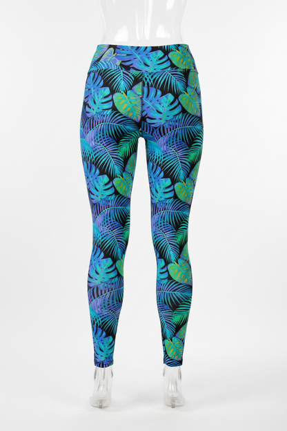A mannequin wearing high-waisted leggings with a tropical leaf print in shades of blue, green, and purple on a black background, shown from the waist down against a plain white studio background.