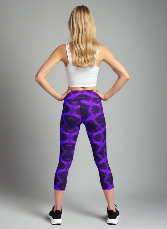 Back view of woman wearing Violet Voltage Yoga Capri leggings with a vivid purple and black lightning-inspired pattern; paired with a white crop top and black athletic shoes, standing against a light grey background.