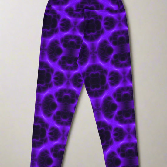 Back view, flat lay of Violet Voltage Yoga Capri leggings featuring a bold purple and black kaleidoscope pattern; displayed on a neutral surface to highlight the vivid, symmetrical design.