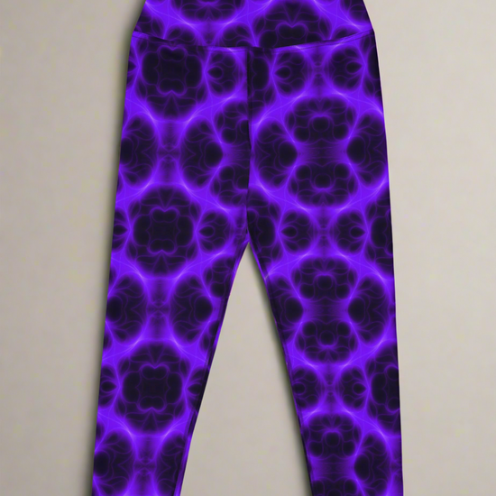 Flat lay, front view of Violet Voltage Yoga Capri leggings featuring a bold purple and black kaleidoscope pattern; displayed on a neutral surface to highlight the vivid, symmetrical design.