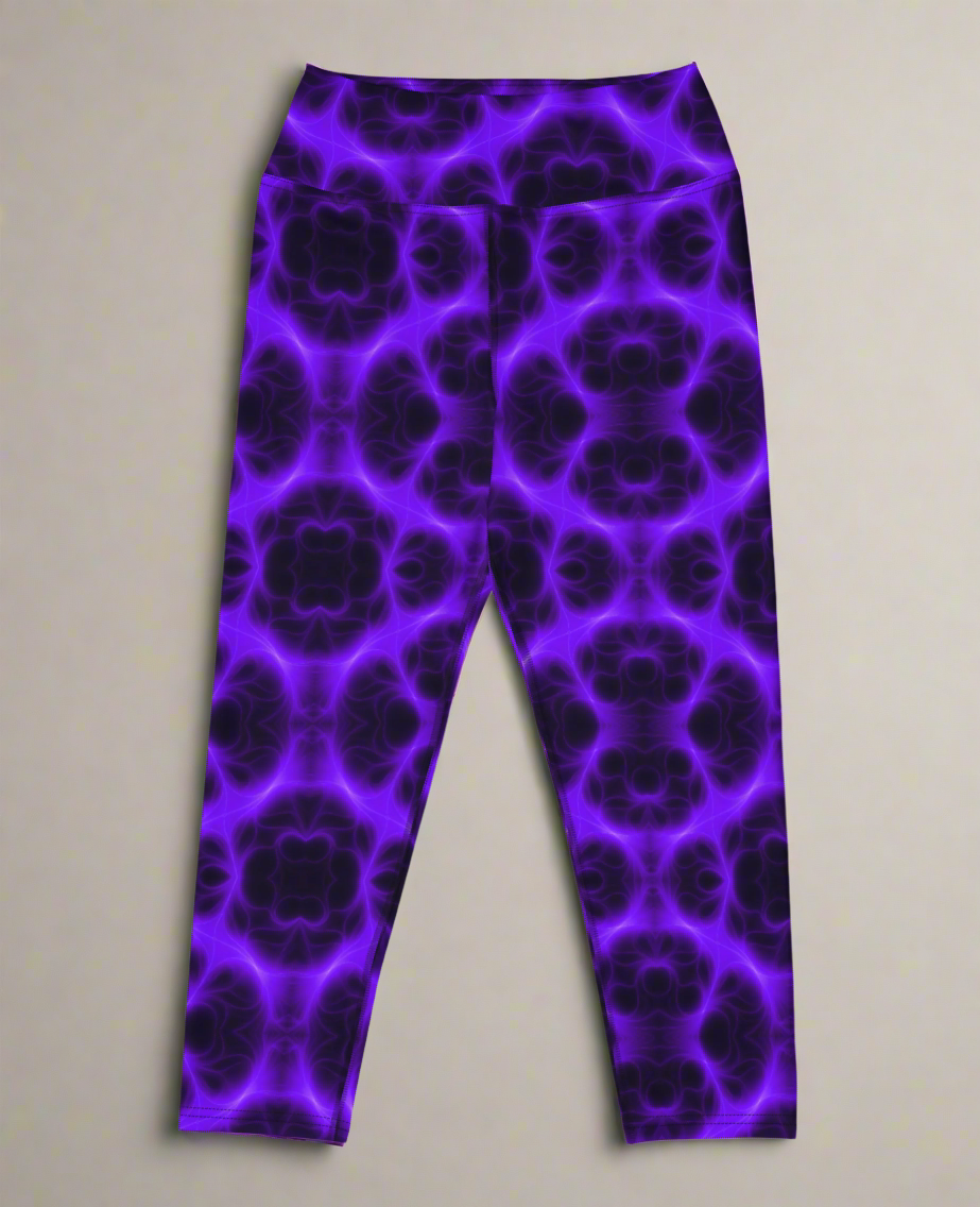 Flat lay, front view of Violet Voltage Yoga Capri leggings featuring a bold purple and black kaleidoscope pattern; displayed on a neutral surface to highlight the vivid, symmetrical design.