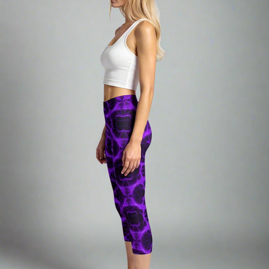 Side profile of woman in Violet Voltage Capri Yoga Leggings with electric purple and black abstract pattern, styled with a white sleeveless crop top and black trainers—capturing luxe activewear for confident, dynamic movement