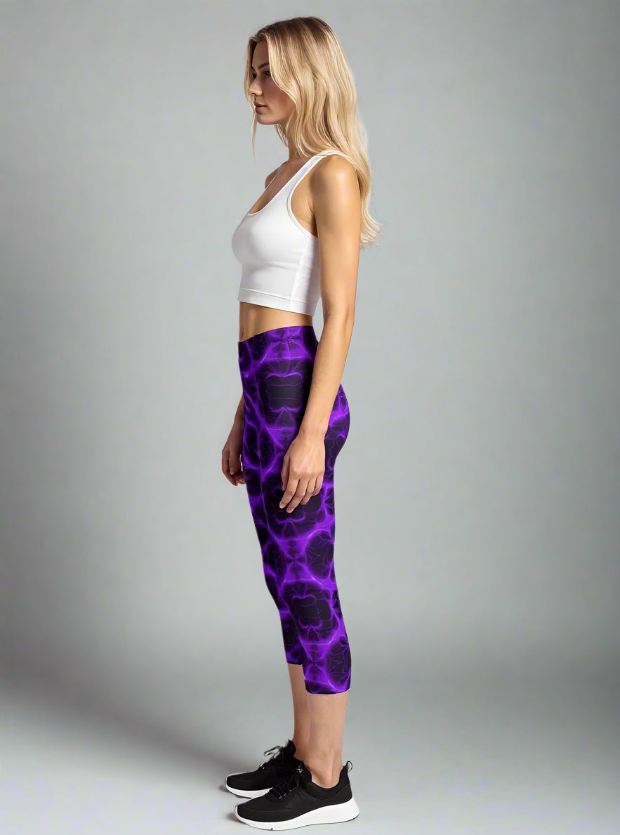 Side profile of woman in Violet Voltage Capri Yoga Leggings with electric purple and black abstract pattern, styled with a white sleeveless crop top and black trainers—capturing luxe activewear for confident, dynamic movement