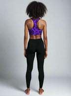 Person wearing a purple sports bra and black leggings on a plain background