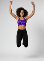 Woman in purple sports bra and black leggings jumping in the air against a gray background