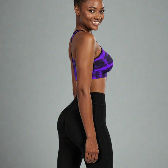 Side view of woman wearing Violet Voltage Essential Active Bra with a bold purple and black electric floral pattern, standing confidently against a plain background