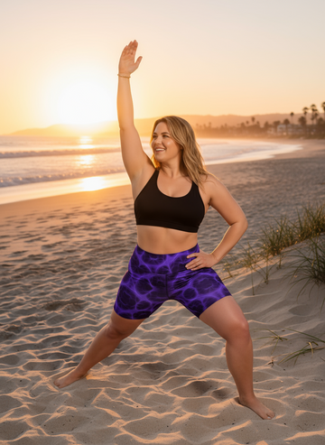 Woman in athletic wear standing on a beach at sunset
