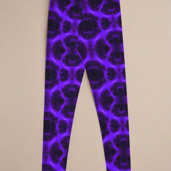Back flat‑lay view of Violet Voltage Yoga Leggings, featuring a bold symmetrical pattern in electric purple and black. Kaleidoscopic, glowing design with repeating circular and floral‑inspired motifs, displayed against a neutral beige background
