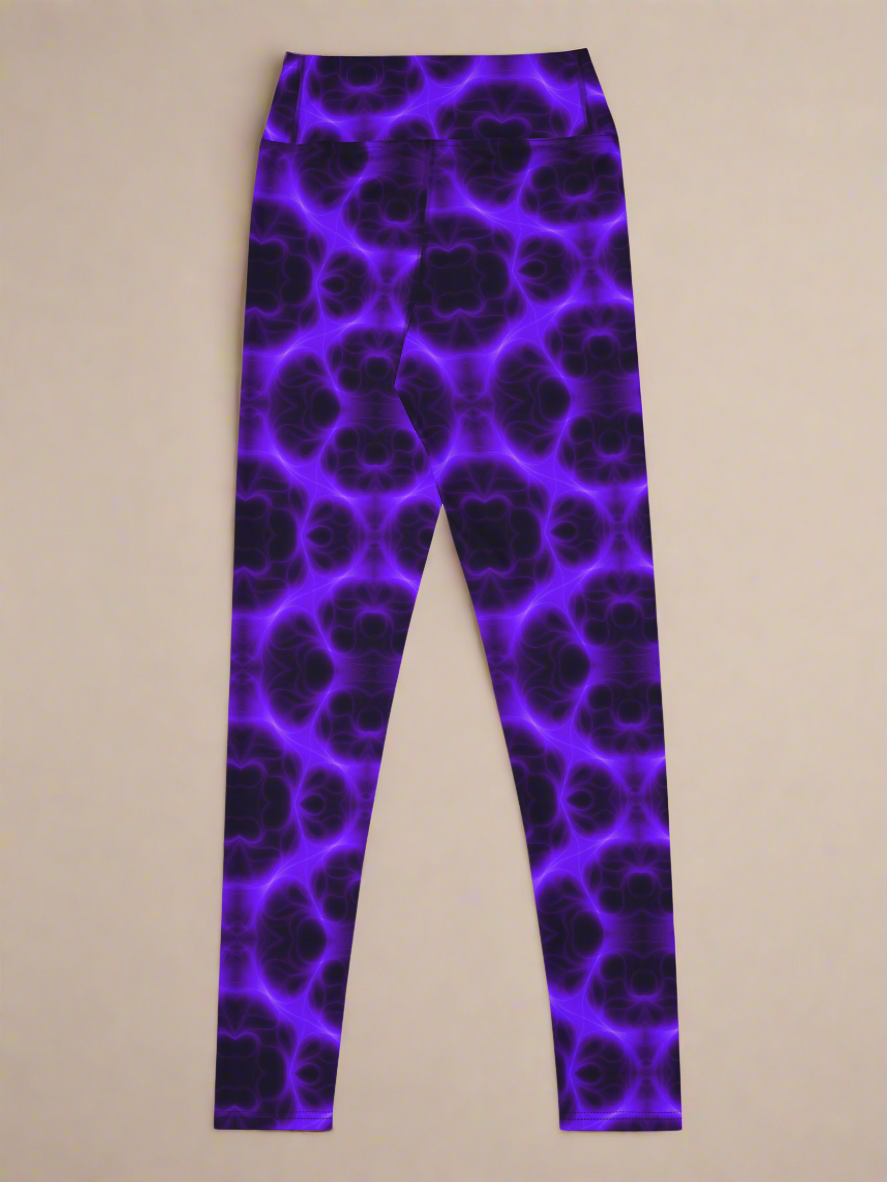 Back flat‑lay view of Violet Voltage Yoga Leggings, featuring a bold symmetrical pattern in electric purple and black. Kaleidoscopic, glowing design with repeating circular and floral‑inspired motifs, displayed against a neutral beige background