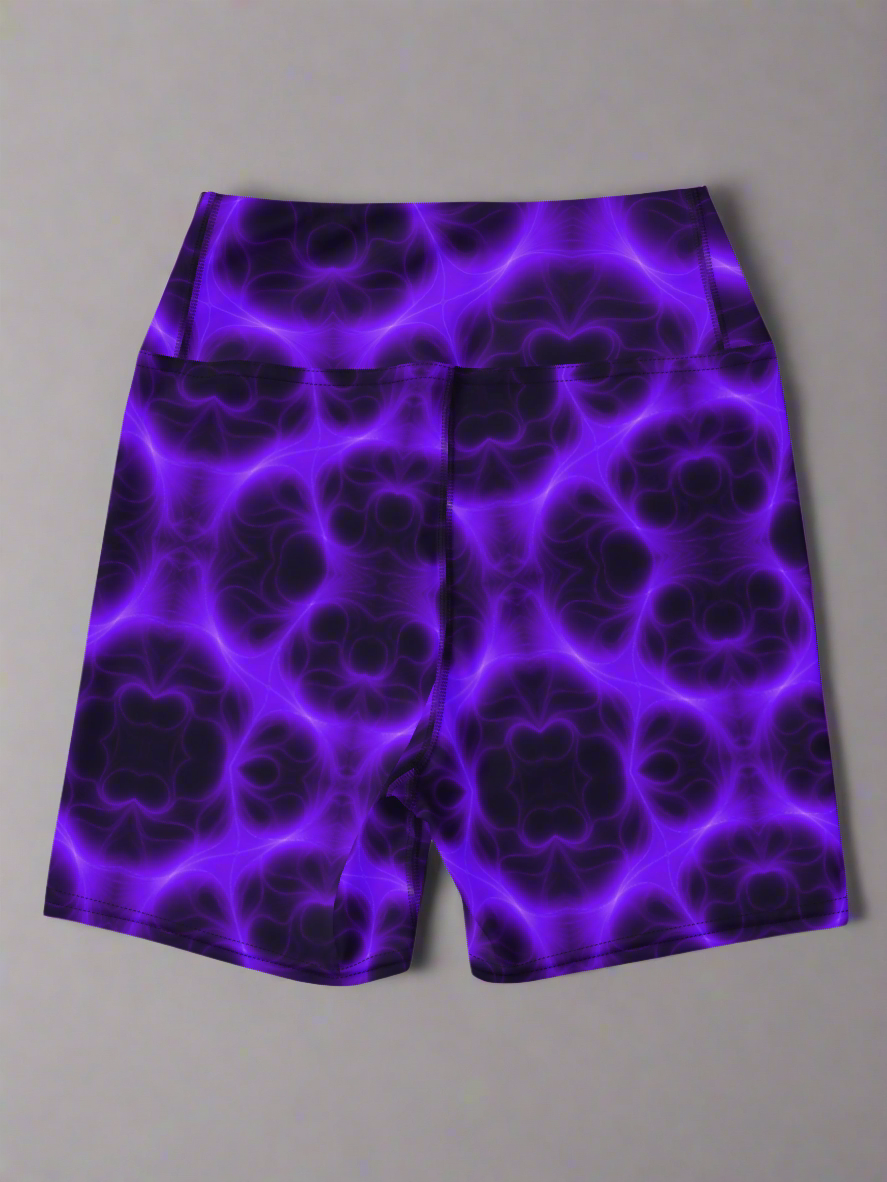 Back view of high‑waisted Violet Voltage yoga shorts with vivid purple and black symmetrical abstract pattern, featuring glowing electric‑inspired design on dark background.