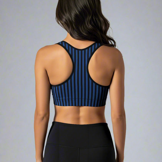 Back view of woman wearing Wednesday Essential Active Bra with bold black and blue vertical stripes, standing against a plain white background