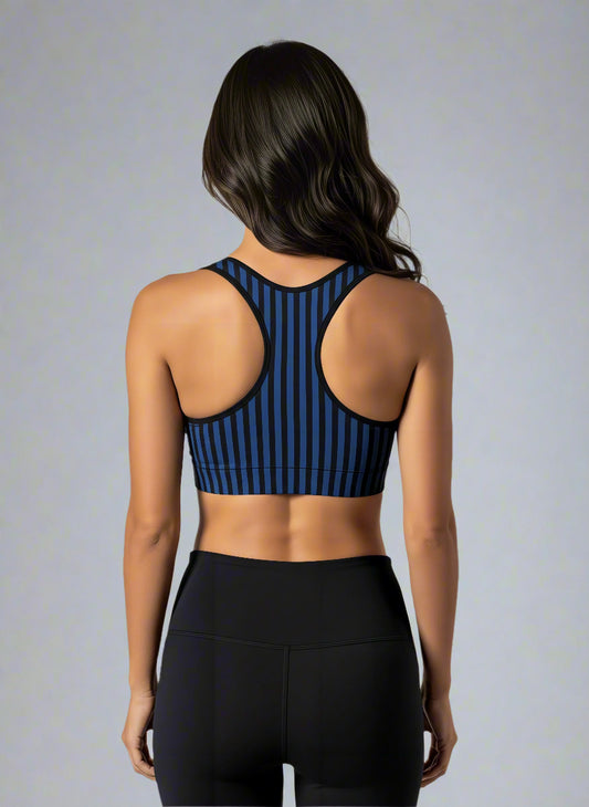 Back view of woman wearing Wednesday Essential Active Bra with bold black and blue vertical stripes, standing against a plain white background