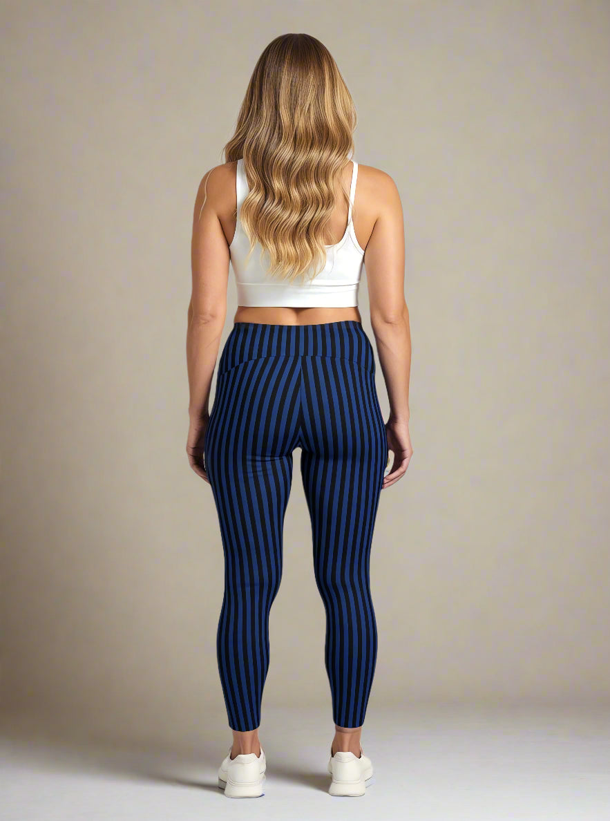 A woman with long, wavy blonde hair is shown from the back, wearing a white sports bra and blue and black vertically striped Wednesday pocket leggings, standing against a plain background with white sneakers.