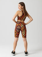 Woman wearing a leopard print sports bra and shorts on a white background
