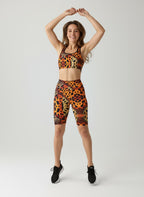 Woman wearing a leopard print sports bra and shorts on a white background