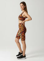 Woman wearing a leopard print sports bra and shorts set on a white background