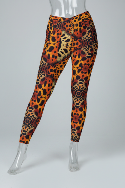 A person modeling high-waisted leggings with an all-over leopard print pattern in orange, black, brown, and beige tones, paired with black sneakers against a light gray studio background.