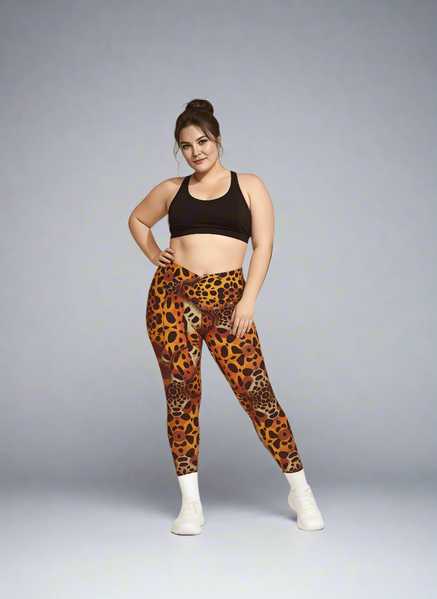 Person standing confidently in Wildfire Crossover Leggings with bold orange leopard print, paired with a black sports bra and white sneakers against a light grey background.