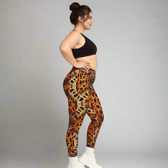 Women in side profile wearing Wildfire Crossover Leggings with bold orange and black leopard print, paired with a black sports bra and white sneakers against a light gray background.
