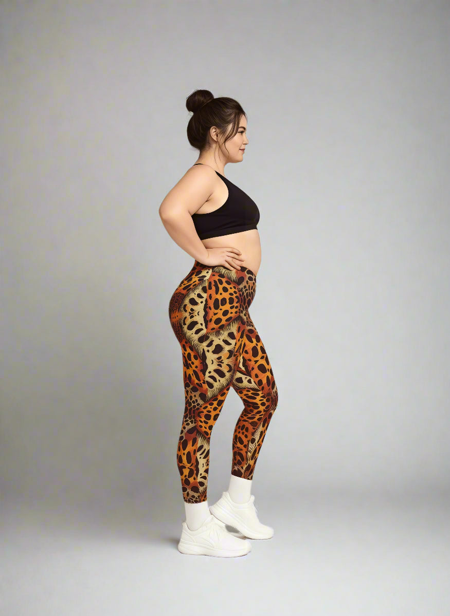 Women in side profile wearing Wildfire Crossover Leggings with bold orange and black leopard print, paired with a black sports bra and white sneakers against a light gray background.