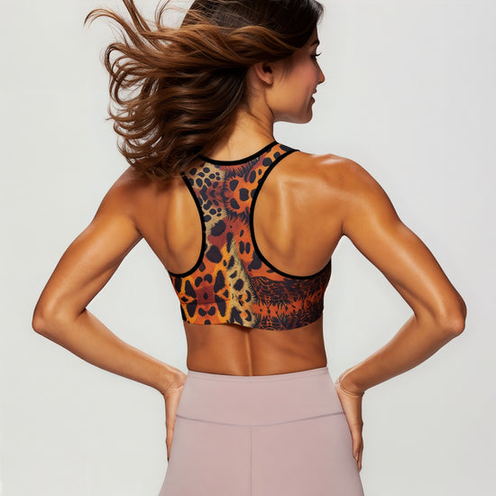 Back view of a woman wearing the Wildfire Essential active bra with a vibrant animal print, showing the racerback design and paired with high-waisted blush leggings
