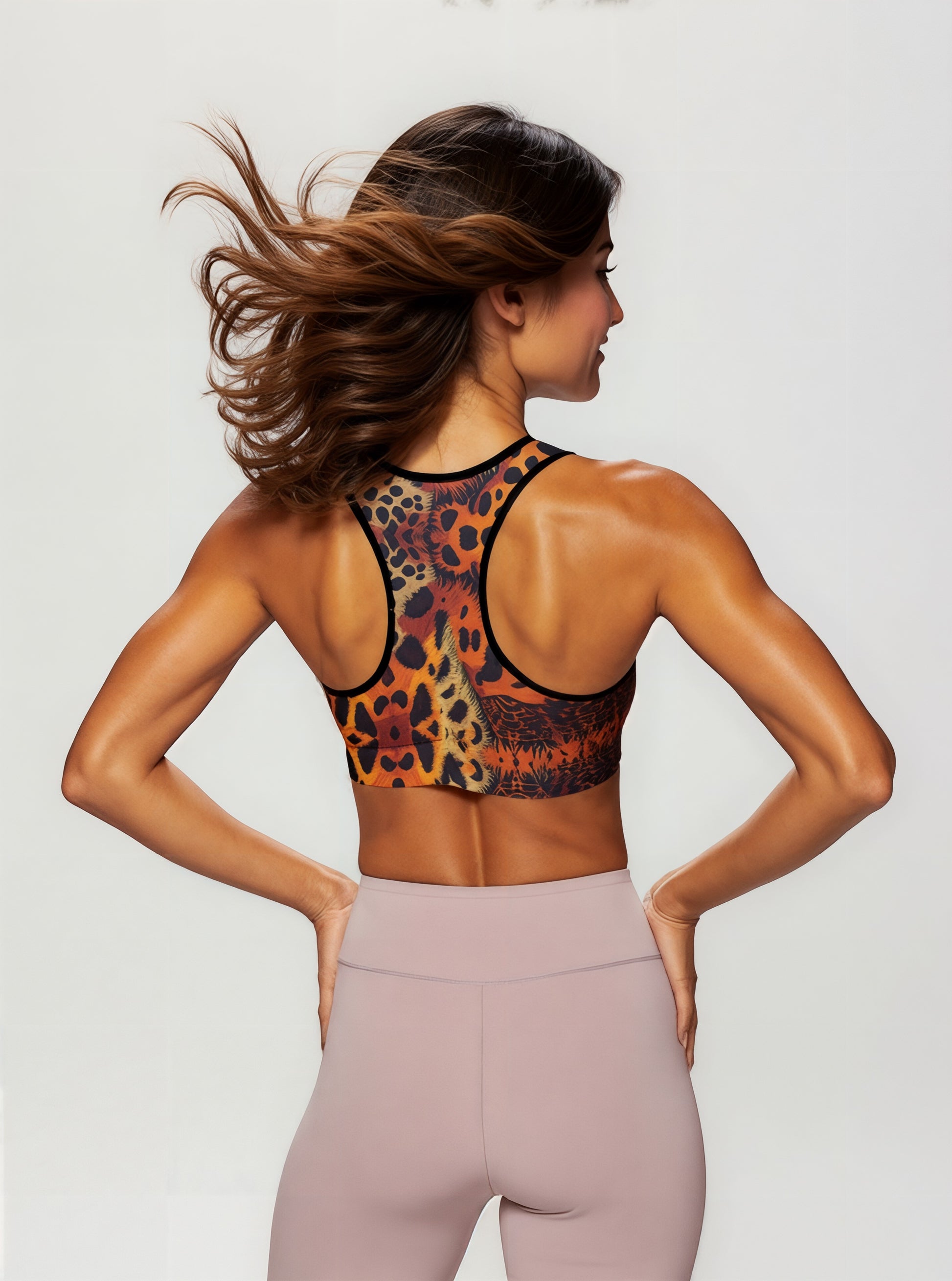 Back view of a woman wearing the Wildfire Essential active bra with a vibrant animal print, showing the racerback design and paired with high-waisted blush leggings