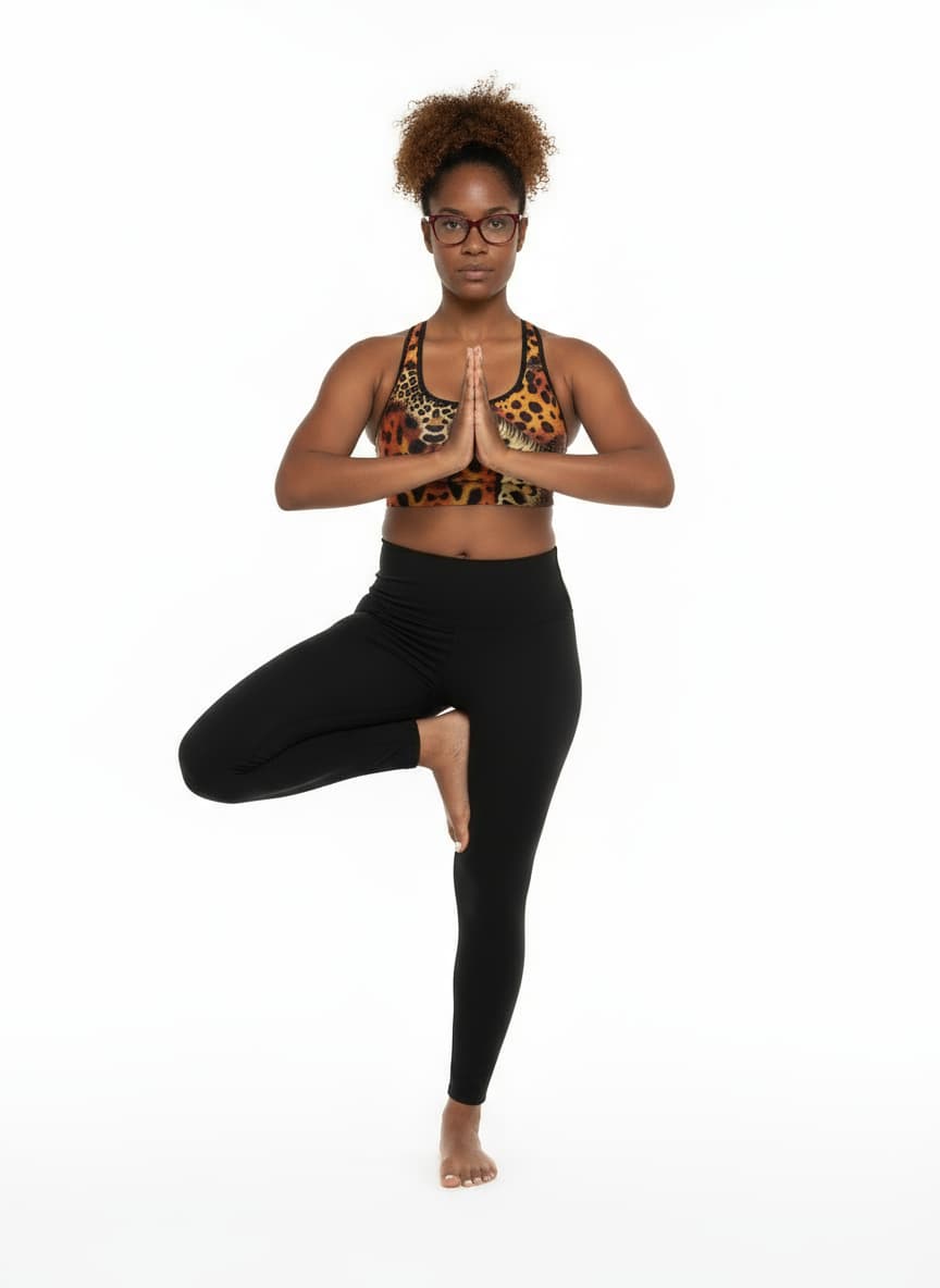 Person wearing a leopard print sports bra and black leggings in a yoga pose on a white background