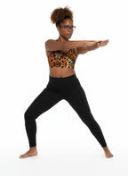 Woman in leopard print sports bra and black leggings posing on a white background