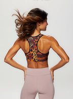 Woman wearing a colorful sports bra and pink leggings on a plain background