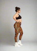 Woman wearing leopard print leggings and a black sports bra on a gray background